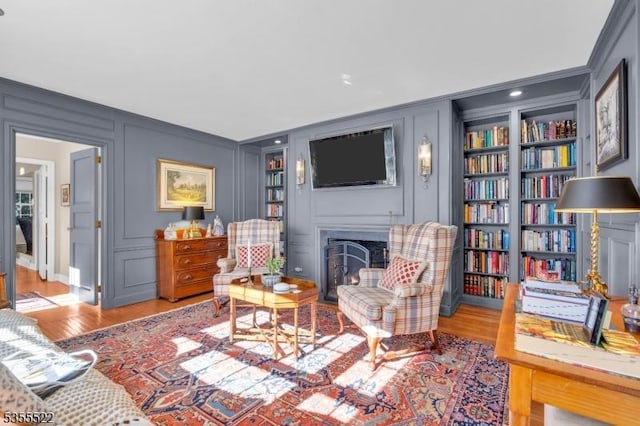 living room with ornamental molding, a decorative wall, and built in shelves