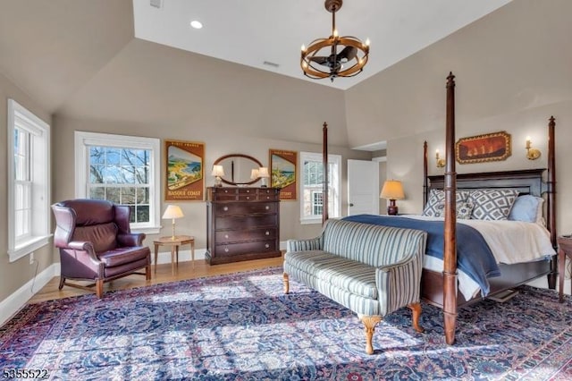 bedroom featuring baseboards, lofted ceiling, wood finished floors, and a notable chandelier