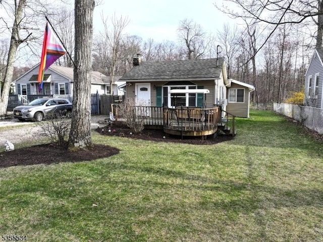 rear view of house with a lawn, a deck, fence, and a chimney