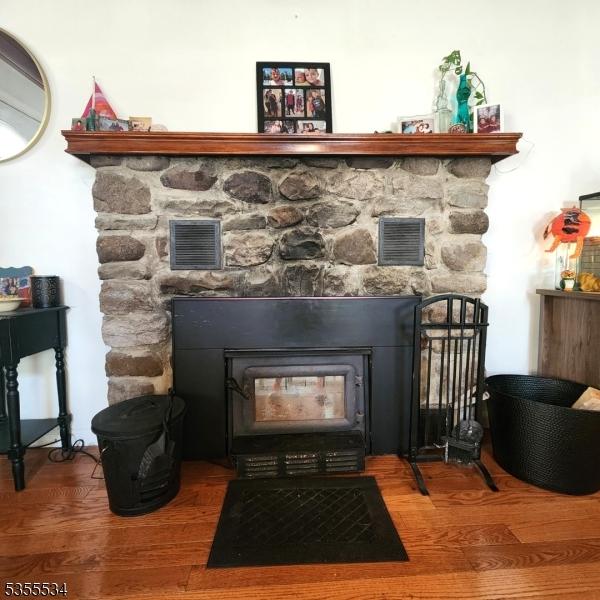 room details with a fireplace, a wood stove, wood finished floors, and visible vents