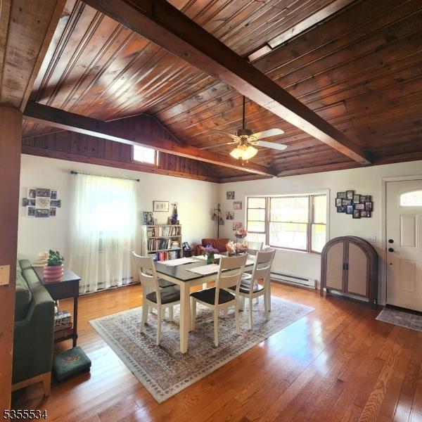 dining space with wooden ceiling, a baseboard radiator, lofted ceiling with beams, and ceiling fan