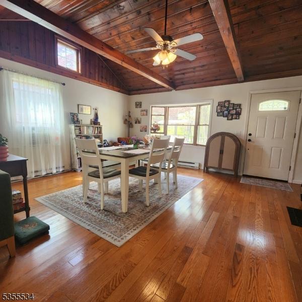 dining space with vaulted ceiling with beams, wood ceiling, ceiling fan, and wood finished floors