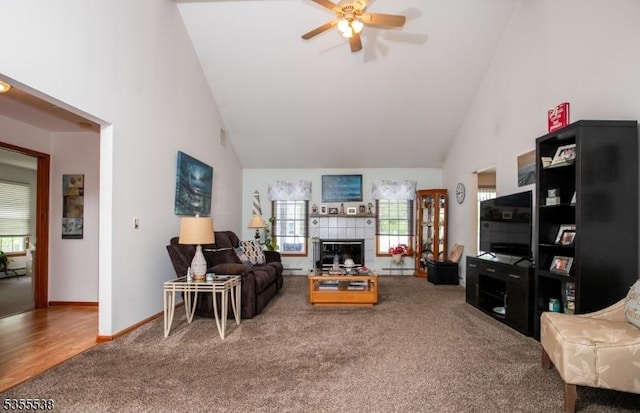 living area with carpet flooring, high vaulted ceiling, ceiling fan, a fireplace, and baseboards