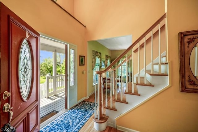 entryway with wood finished floors, stairway, and baseboards