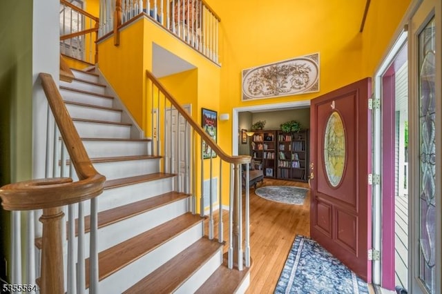 entryway with a high ceiling, stairs, and wood finished floors