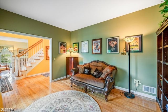 living area featuring light wood-style floors, stairway, and baseboards