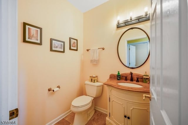 bathroom with toilet, vanity, tile patterned flooring, and baseboards
