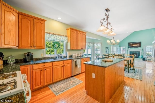 kitchen featuring stainless steel dishwasher, a kitchen island, gas range gas stove, light wood-style floors, and decorative light fixtures