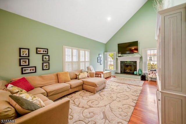 living area with high vaulted ceiling, a premium fireplace, wood finished floors, plenty of natural light, and recessed lighting