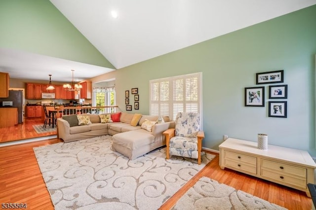 living room with high vaulted ceiling, light wood-style floors, and a chandelier