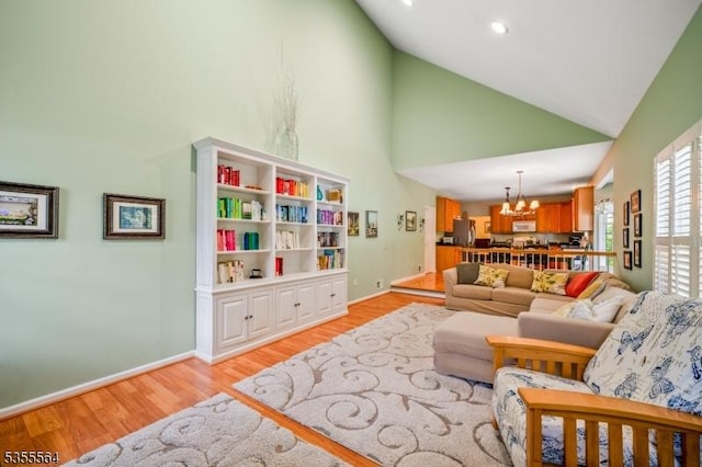 living room featuring a chandelier, light wood-style floors, high vaulted ceiling, and baseboards