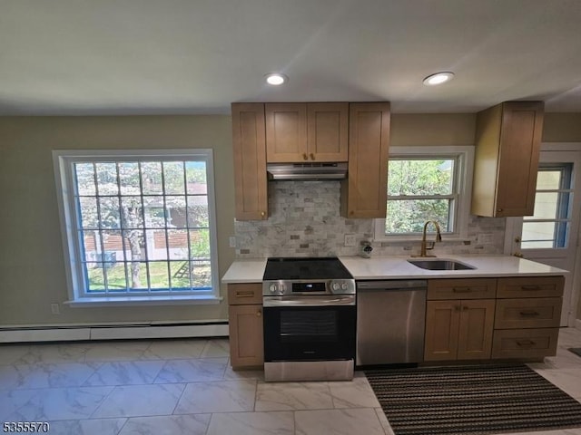 kitchen featuring appliances with stainless steel finishes, a sink, a baseboard radiator, under cabinet range hood, and light countertops