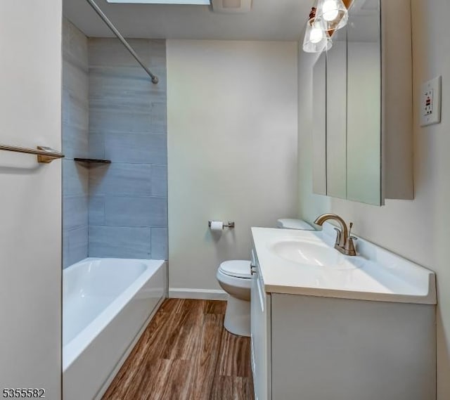 full bathroom featuring wood finished floors, vanity, toilet, baseboards, and bathing tub / shower combination
