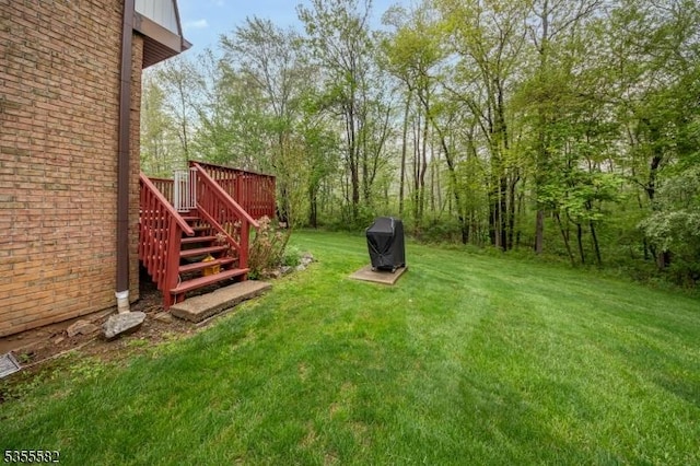 view of grassy yard with stairway and a deck
