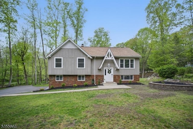 raised ranch with a front lawn and brick siding