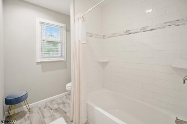 bathroom with toilet, shower / bath combo with shower curtain, and baseboards