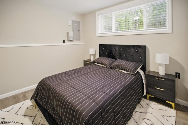 bedroom with light wood-style flooring, baseboards, and electric panel