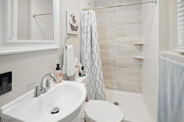 bathroom with a sink, a shower stall, and toilet