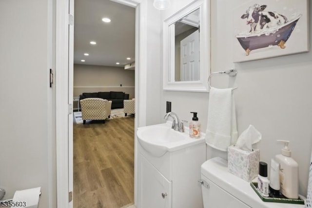 bathroom with wood finished floors, vanity, toilet, and recessed lighting