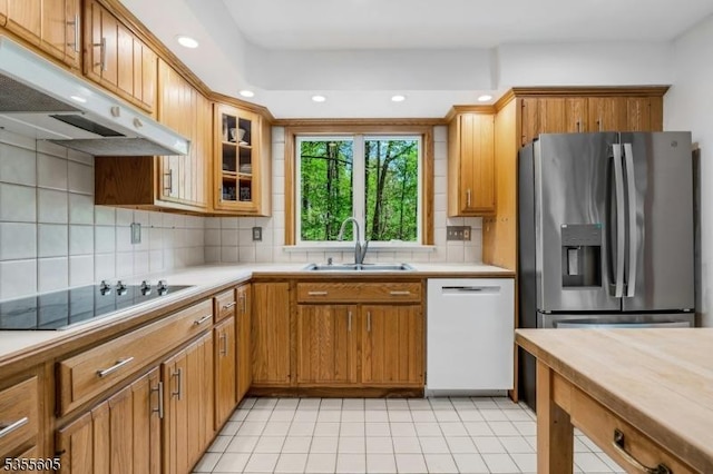 kitchen with stainless steel fridge with ice dispenser, white dishwasher, under cabinet range hood, a sink, and black electric cooktop