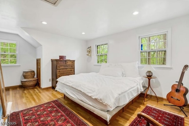 bedroom with multiple windows, wood finished floors, baseboards, and recessed lighting