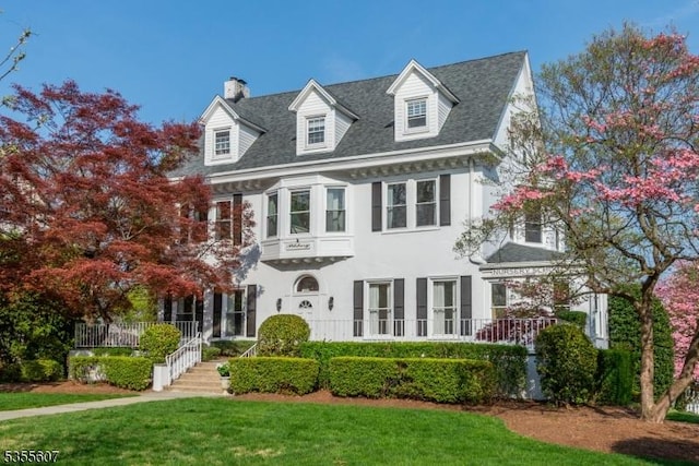 view of front of house with a chimney, a front lawn, and stucco siding