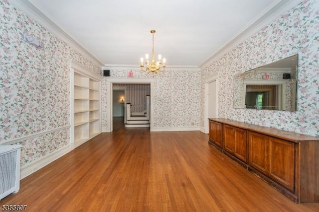 unfurnished dining area featuring wallpapered walls, a chandelier, wood finished floors, radiator, and ornamental molding