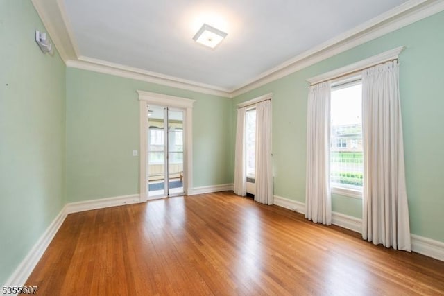 unfurnished room with crown molding, wood finished floors, and baseboards