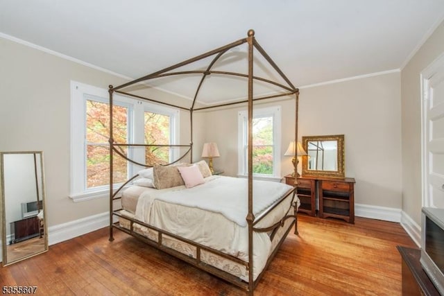bedroom with baseboards, ornamental molding, and wood finished floors