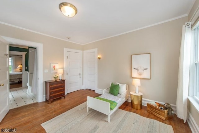 bedroom with wood finished floors, crown molding, and baseboards