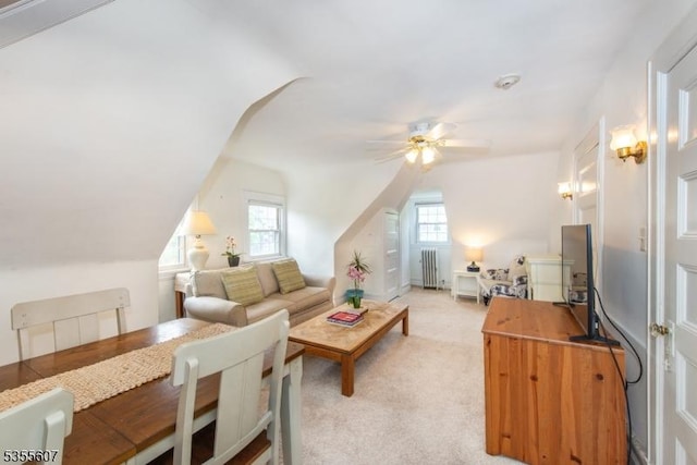 living room with radiator heating unit, a ceiling fan, vaulted ceiling, and light carpet