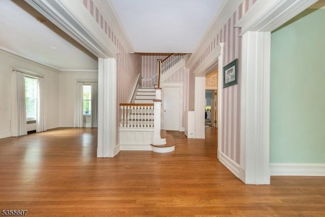 bonus room featuring wallpapered walls, wood finished floors, stairs, baseboards, and radiator heating unit