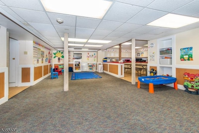 rec room with carpet floors, built in features, and a paneled ceiling