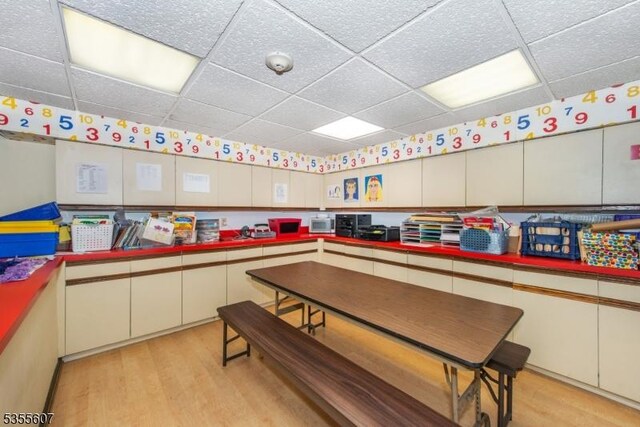 playroom with a paneled ceiling and light wood finished floors