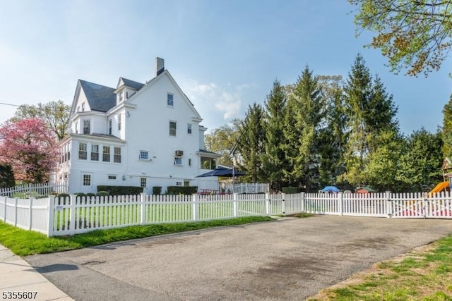 view of property exterior featuring a chimney and a fenced front yard