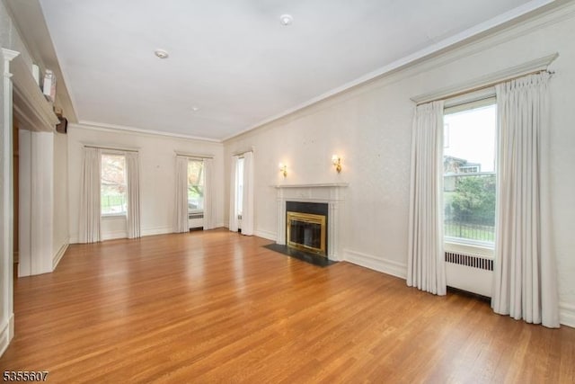 unfurnished living room featuring light wood-type flooring, a high end fireplace, and crown molding