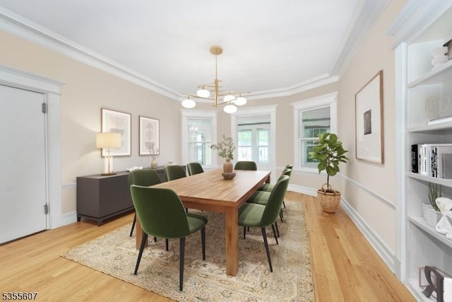 dining room with a chandelier, ornamental molding, and light wood-style floors