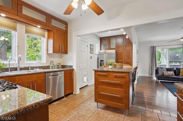 kitchen with stainless steel appliances, a ceiling fan, a sink, and glass insert cabinets