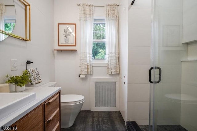 bathroom featuring toilet, a stall shower, vanity, wood finished floors, and radiator heating unit