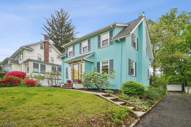 back of property featuring a chimney, a lawn, stucco siding, and a garage