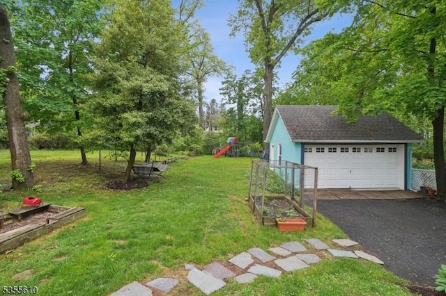 view of green lawn featuring a garden, a detached garage, a playground, and an outdoor structure