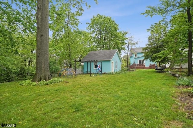 view of grassy yard featuring an outdoor structure, a wooden deck, and a storage unit