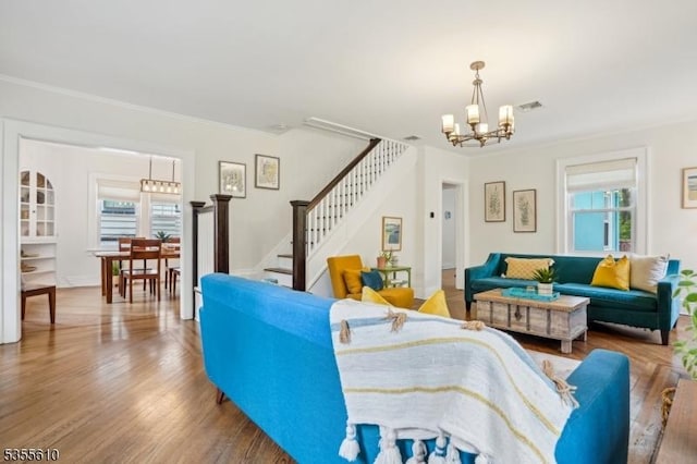 living room featuring a chandelier, stairway, crown molding, and wood finished floors