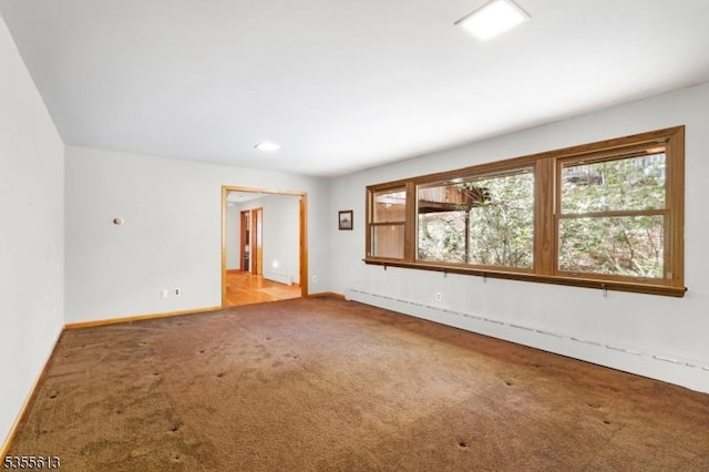 unfurnished room featuring carpet, baseboards, and baseboard heating