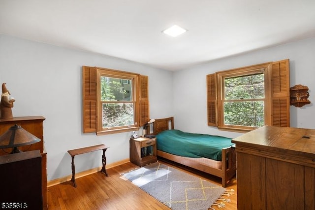 bedroom featuring light wood-style floors, baseboards, and multiple windows