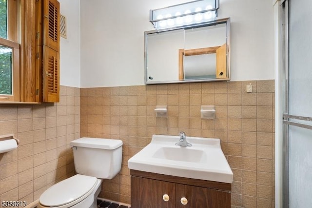 full bathroom with wainscoting, a shower with door, tile walls, and toilet
