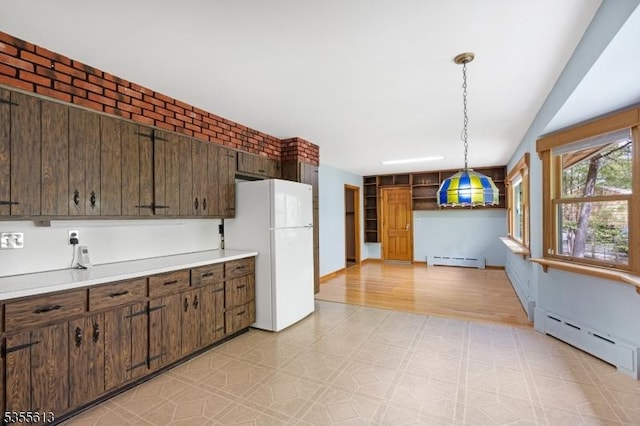 kitchen with a baseboard radiator, light floors, light countertops, and freestanding refrigerator
