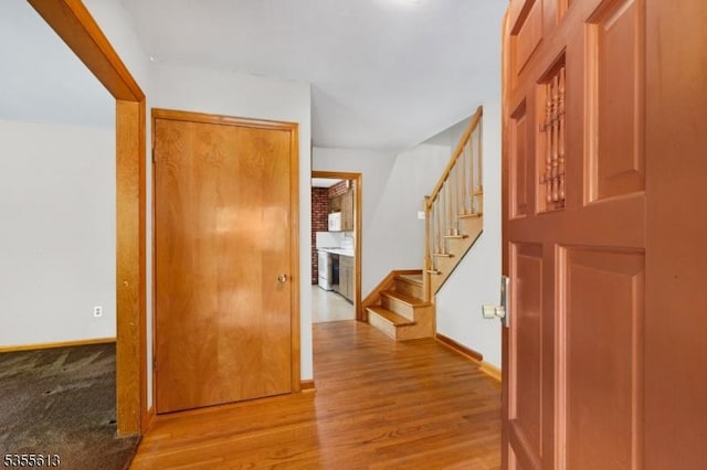 corridor with baseboards, stairway, and wood finished floors