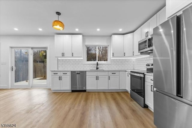 kitchen with a wealth of natural light, light wood-style floors, stainless steel appliances, and a sink