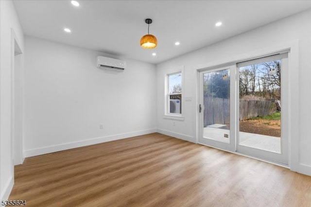 interior space with baseboards, recessed lighting, light wood-style floors, and a wall unit AC